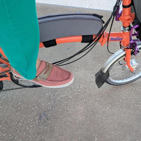 A photo of my right foot on the pedal of an

orange Brompton folding bike with its name, Huffer, in purple on the top tube

I'm wearing
mauve loafers with under a green pantleg with no socks