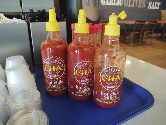 3 bottles of off brand Sriracha sauce each labeled as "Cha!"