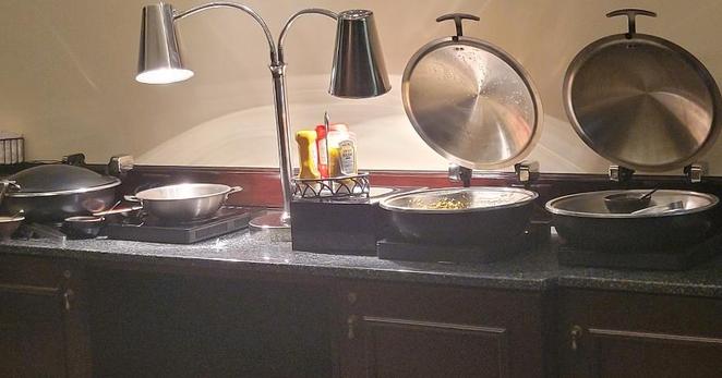 banquet table with dark covering and empty stainless serving dishes