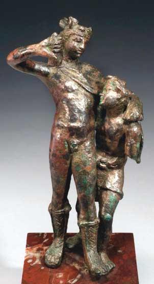 Bronze figurine of the god Dionysos supported by his satyr boyfriend Ampelos.
The youthful god of wine, having over-imbibed, holds an upturned rhyton (wine horn) in his right hand. He wears only a chlamys and high laced travelling boots and wreath about his head.