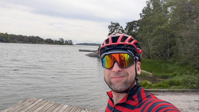 Selfie Porkkalanniemen merimaisemassa. Asuna punasiniraidallinen pyöräilypaita, punainen pyöräilykypärä ja nopeet lasit.