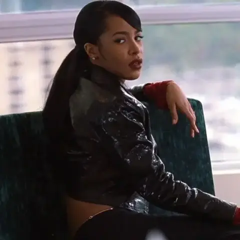 American musician, dancer and actress Aaliyah Haughton as Trish O’Day in the 2000 action romance film “Romeo Must Die”. She is wearing a dark leather jacket and is looking over her shoulder. 
