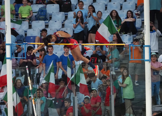 Italian pole vaulter crosses the bar with spectators looking on.