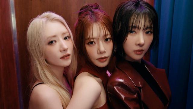 A screenshot from the "2 Months" music video, showing the 3 members in a close-up inside a photo booth. They're wearing dark red clothes and standing close to each other, posing for the camera.