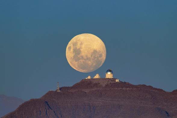 Another night of observing begins at the U.S. National Science Foundation Cerro Tololo International Observatory (CTIO) in the Chilean Andes, a Program of NSF NOIRLab, as the Moon sets below the horizon. The Moon appears massive and with a mysterious yellowish glow as it retreats behind the SMARTS–GSU 0.9-meter Telescope on the left, the SMARTS–GSU 1.5-meter Telescope in the center, and the Víctor M. Blanco 4-meter Telescope on the right.