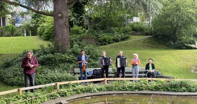 Un homme présente un groupe musical dans un part avec un étang