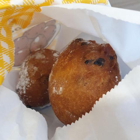 A paper bag with krentenbollen (fried dough balls with raisina) and sugar. They look delicious. 