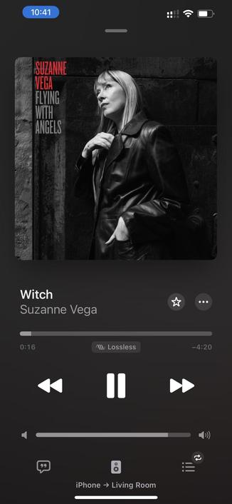 The image shows a music player interface displaying the song "Witch" by Suzanne Vega. The album cover features a black and white photograph of Vega in a leather jacket looking thoughtfully upwards, with the album title "Flying with Angels" prominently displayed. 