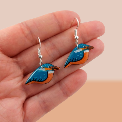 Boucles d'oreilles fantaisie pendantes éco-responsables en forme de martin-pêcheurs.
Les perles sont réalisées en CD recyclé, découpées et peintes à la main, puis recouvertes de résine époxy.
Les attaches sont en laiton argenté, mais sont aussi disponibles dans d'autres métaux et coloris.