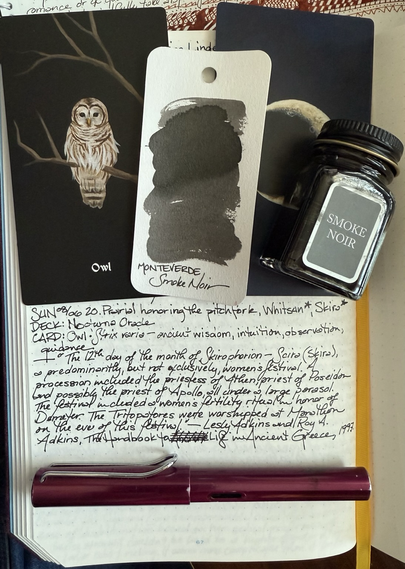 Open notebook with handwritten text from the post in the middle of the page with additional text: “The 12th day of the month of Skirophorion - Scira (Skira), a predominantly, but not exclusively, women's festival. A procession included the priestess ofAthena, priest of Poseidon and possibly the priest of Apollo, all under a large parasol. The festival included a women's fertility ritual in honor of Demeter. The Tritopatores were worshiped at Marathon on the eve ofthis festival.” — Lesley Adkins and Roy A. Adkins, The Handbook of Life in Ancient Greece, 1997. Above the text is a black card with a brown and white owl sitting on a branch, another branch above it. Next to the card is the swatch of a medium gray ink and an almost empty bottle of Smoke Noir ink both lying on top of a card with a crescent moon on the back. Under the text purplish, wine-colored fountain pen lies across the page. 