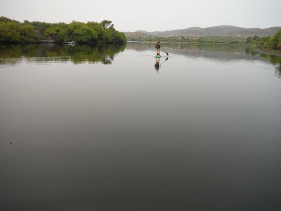 A lone woman paddling a SUP and an empty lake