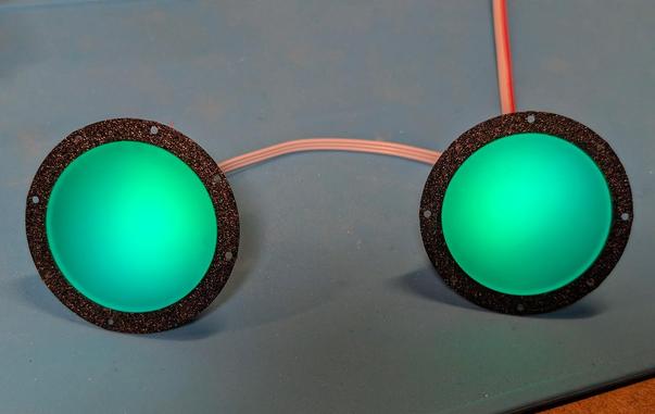 Two green glowing circles with black border. They're spaced about eye-distance apart. The black border has holes in it.