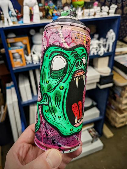 Spray can art with an illustration of a green monster getting ready to chomp you.