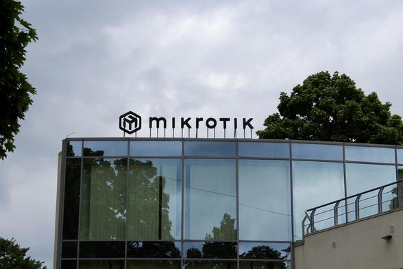 Photo of the roofline of the MikroTik RouterOS Training Centre. The wall is made from glass and on the roof is a black sign with the new MikroTik Logo