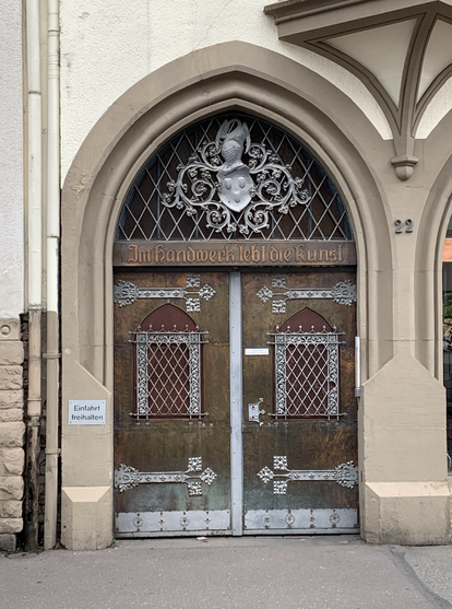 kunstvoll beschlagenes Portal mit der Aufschrift „Im Handwerk lebt die Kunst“