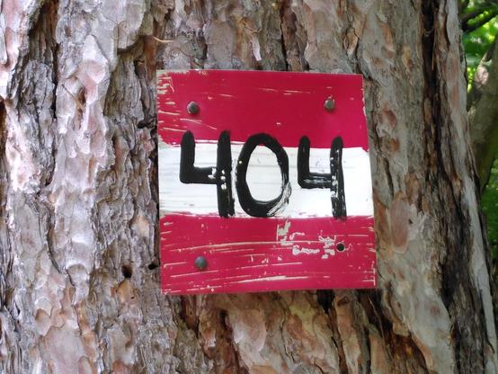 Ein auf einen Baum angebrachtes quadratisches Schild, rotweißrot mit schwarz aufgemalter Nummer 404. Aufnahmeort an der Goldenen Stiege bei Mödling.