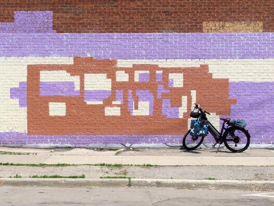 A parked bicycle next to a colourful wall.