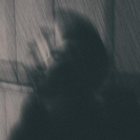 This is Will Régnier's press shot consisting of a blurry silhouette of a person against a striped grey background, creating a mysterious and shadowy mood. 