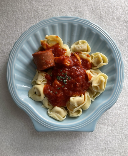 The plate is in the shape of a shower inside tortellini red sauce, a pepperoni seasoned with basil