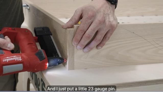 Door jamb assembly nailing two pieces of oak together. Video screenshot with the caption "And I just put a little 23 gauge pin..." 