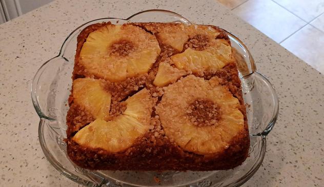 A cake is golden brown with rings of pineapple on top and a caramelized oatmeal topping between the rings.