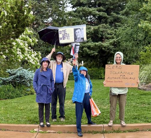 A cluster of demonstrators in rain gear, holding signs that say Free David and Abolish ICE. 