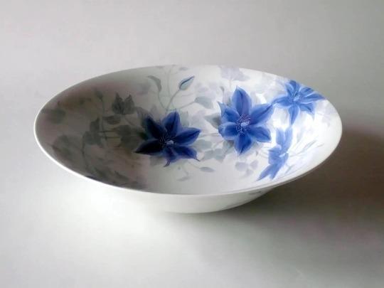 A white bowl with blue Clematis flowers.
