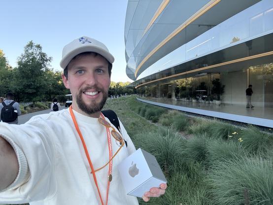 Selfie of me holding my Apple Design Award on front of the Apple Park