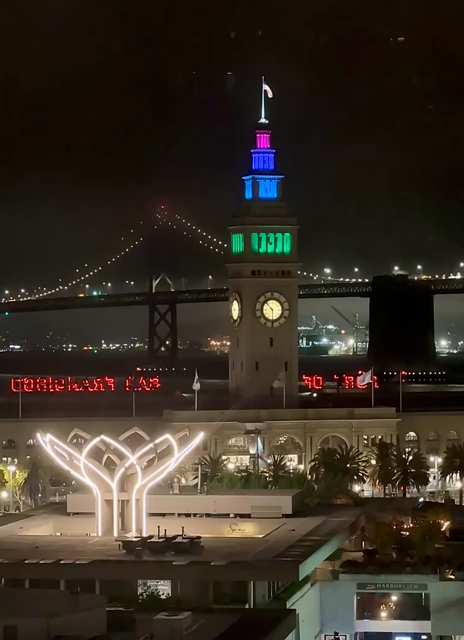 Time lapse video of the San Francisco ferry building clock tower at night as it alternates different colors during pride month