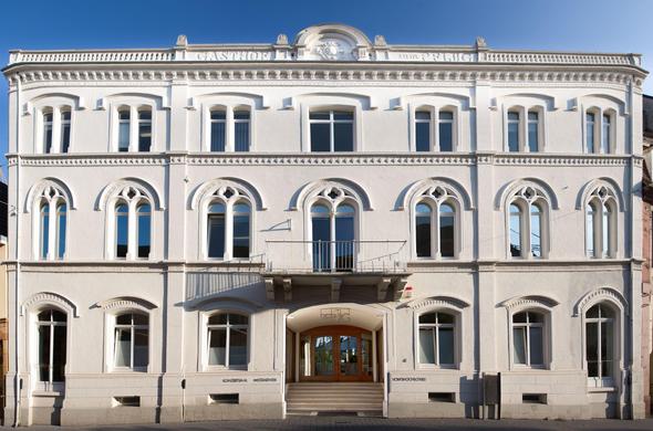 Außenansicht des Haus zum Pflug in Lahr, in dem die Volkshochschule zu finden ist, ein helles Gebäude mit vielen Rundbogenfenstern