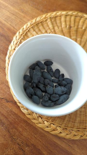 A white pot with a good handful of purplish small fruit like small swollen torpedo blueberries. 

The pot is sitting on a round mat of cane work, and that is on a wooden surface.