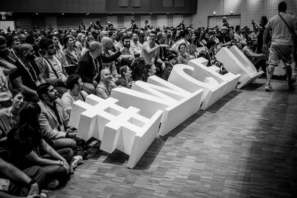 WordCamp Europe attendees sitting on the floor with big physical #WCEU letters, during the annual group photo. (Photo: Florian Ziegler)