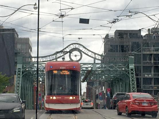 A vibrant red and white trolley traveling down a bustling street, with shops and people in the background.