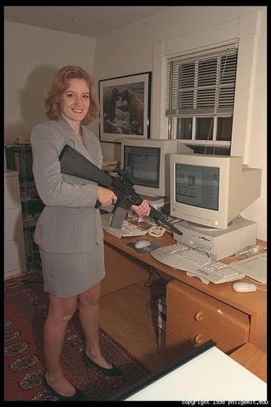 woman in business suit points a rifle at old computers