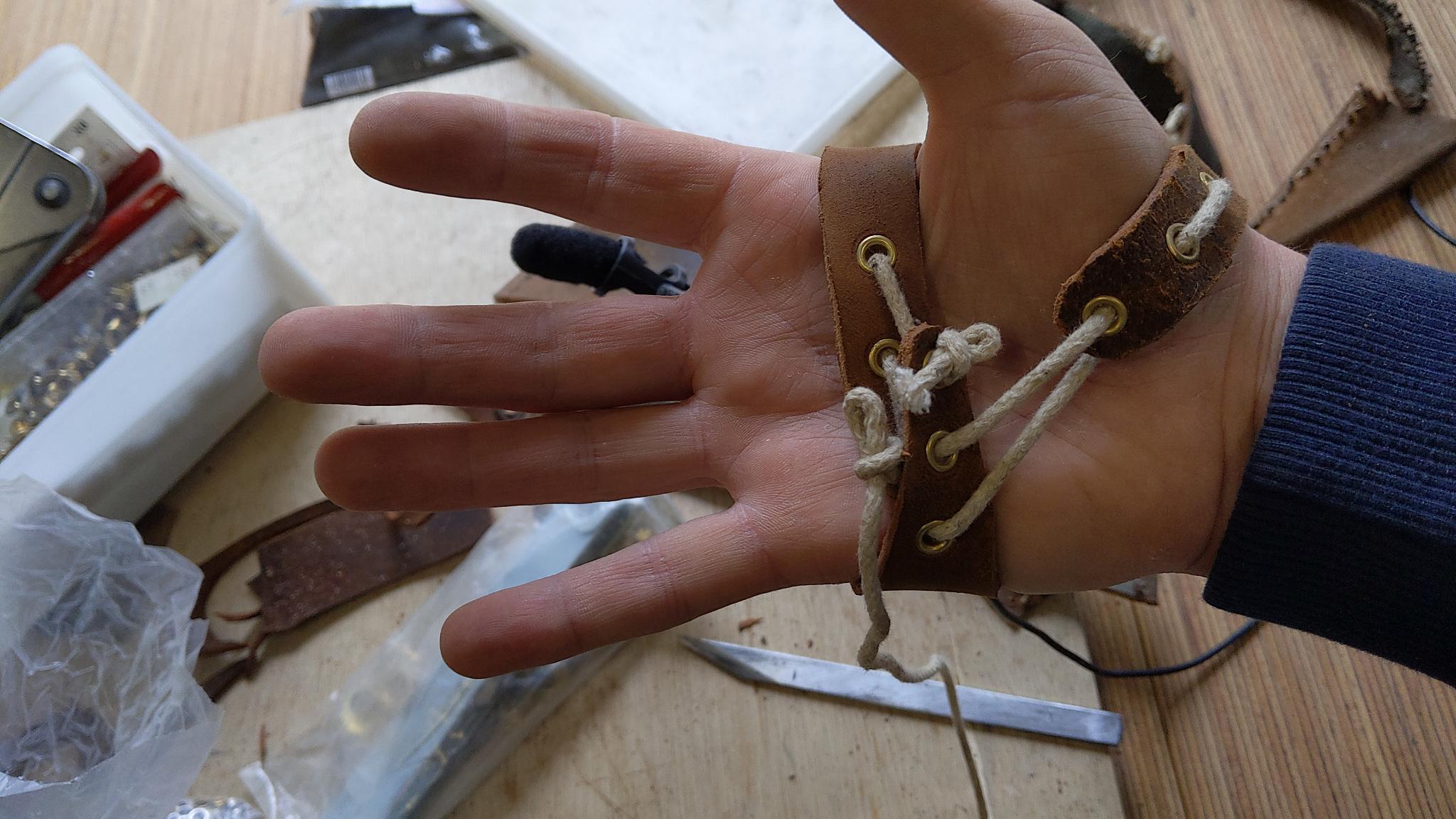 On voit la fixation en corde d'un montage cuir qui fixe un micro sur le dos de la main.