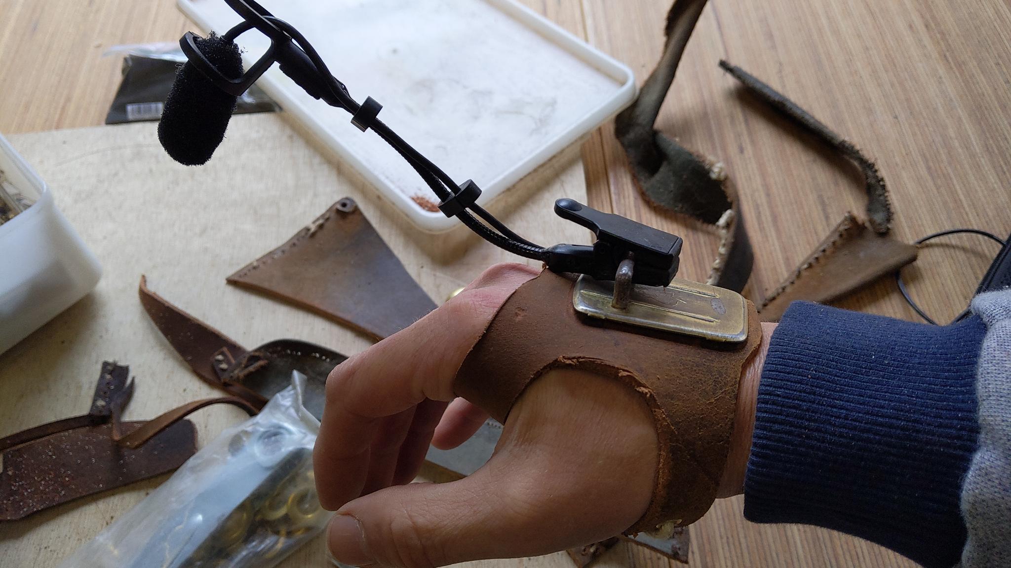 On voit une gaine constituée de cuir qui fixe un micro sur le dos de la main.