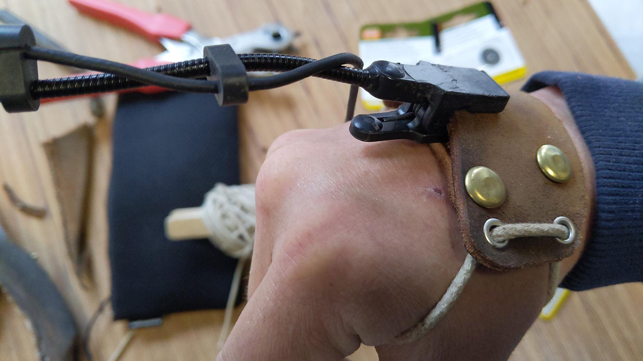 On voit une gaine constituée de deux pièces de cuir qui fixent un micro sur le dos de la main.