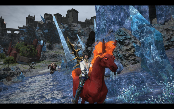 A warrior with dark hair and wearing ornate armor and clothing rides a vibrant red, fiery horse with glowing red eyes through a rocky landscape dotted with blue crystal formations and small white flowers. A goblin pursues them, carrying an axe. In the background, a ruined castle sits on a cliff under a gray sky.