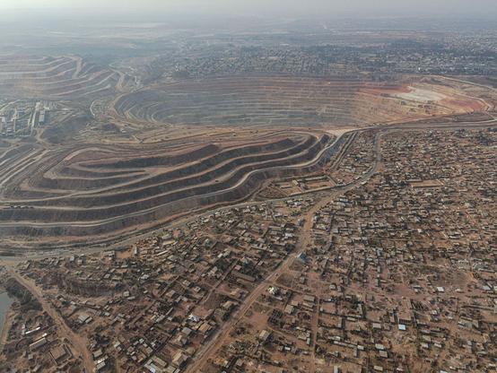 An aerial view of an open pit Cobalt and Copper mine in DRC Congo, and the neighborhoods and housing surrounding the mine.  