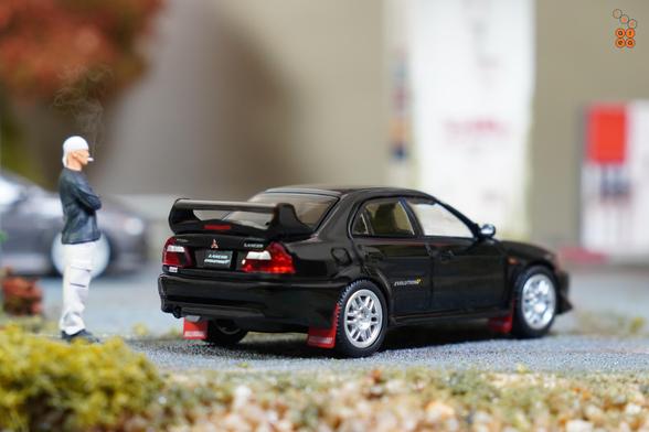 A right side of Mitsubishi Lancer GSR Evolution V 1998 with Mud Flap, Pyrenees Black by Hobby Japan in 1:64 scale with 1:64 figure on AREA 164