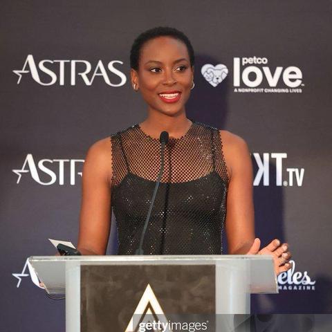 Tracy Ifeachor at the Astra TV Awards, accepting the prize for "The Pitt". Tracy wears a black form-fitting net dress without sleeves + a strong red lip.
