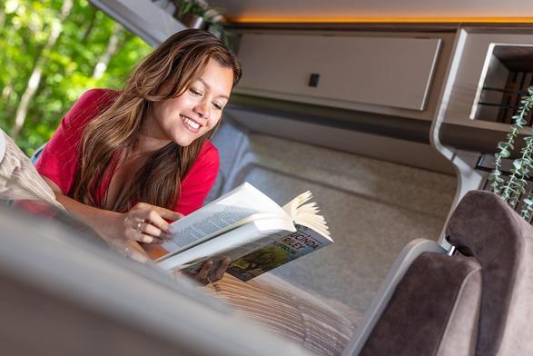 Advertising photography voor a camper interiors company, showing a lady lying on bed reading a book and showing relaxation