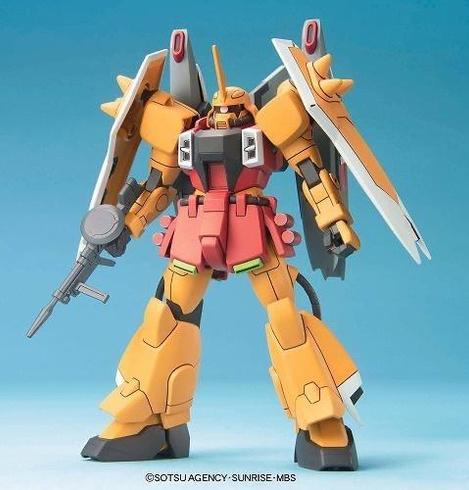 A detailed model of a robotic figure, featuring a striking orange and pink color scheme, equipped with large shoulder armor and wings. The figure holds a gun in one hand and is posed against a light blue background.