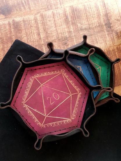 Leather dice tray in form of D20 in front of a black and wood background