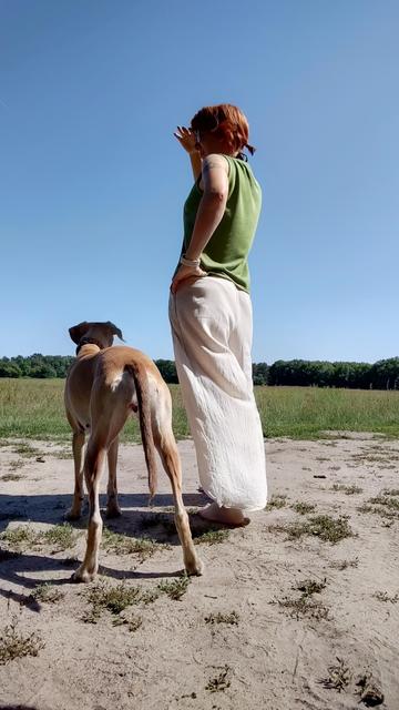 Ylvi und ich, aufgenommen von hinten wie wir in die Ferne schauen. Ich trage eine helle, luftig weite Leinenhose und ein grünes ärmelloses Top.