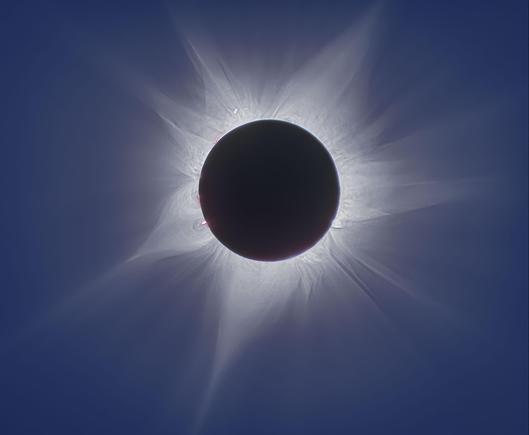 A composite image of the April 20, 2023 hybrid solar eclipse, captured from a ship in the Indian Ocean. The Moon fully covers the Sun, revealing the Sun’s delicate outer atmosphere — the solar corona — extending outward in soft, wispy streamers. The image blends 11 exposures of varying lengths to show fine structures not visible to the naked eye. The background is a deep black sky. This photograph was taken by Fred Espenak, a renowned eclipse expert who passed away in 2025.