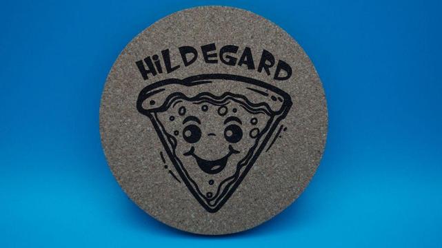 Runder Korkuntersetzer mit einem fröhlich gravierten Pizzastück und dem Namen Hildegard – ideal für Kindergeburtstage.