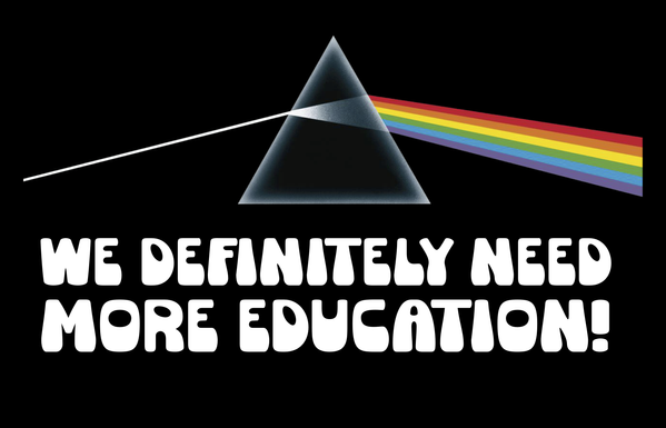 A sign saying "We Definitely Need More Education!" with a Pink Floyd prism triangle thing on it.