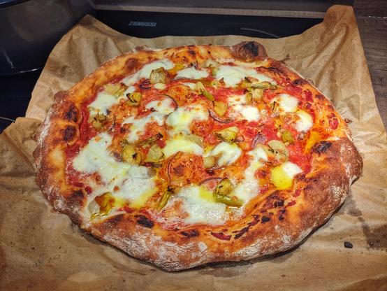 Pizza with mozzarella , artichoke, some chillis, and a little but of pink onion.