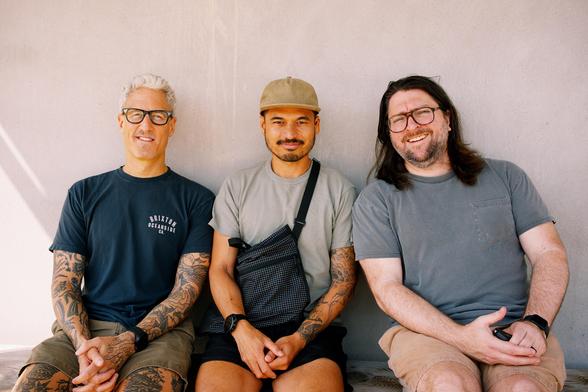 Three men sit on a bench! Are we remarkable enough for this alt text? The jury is out.